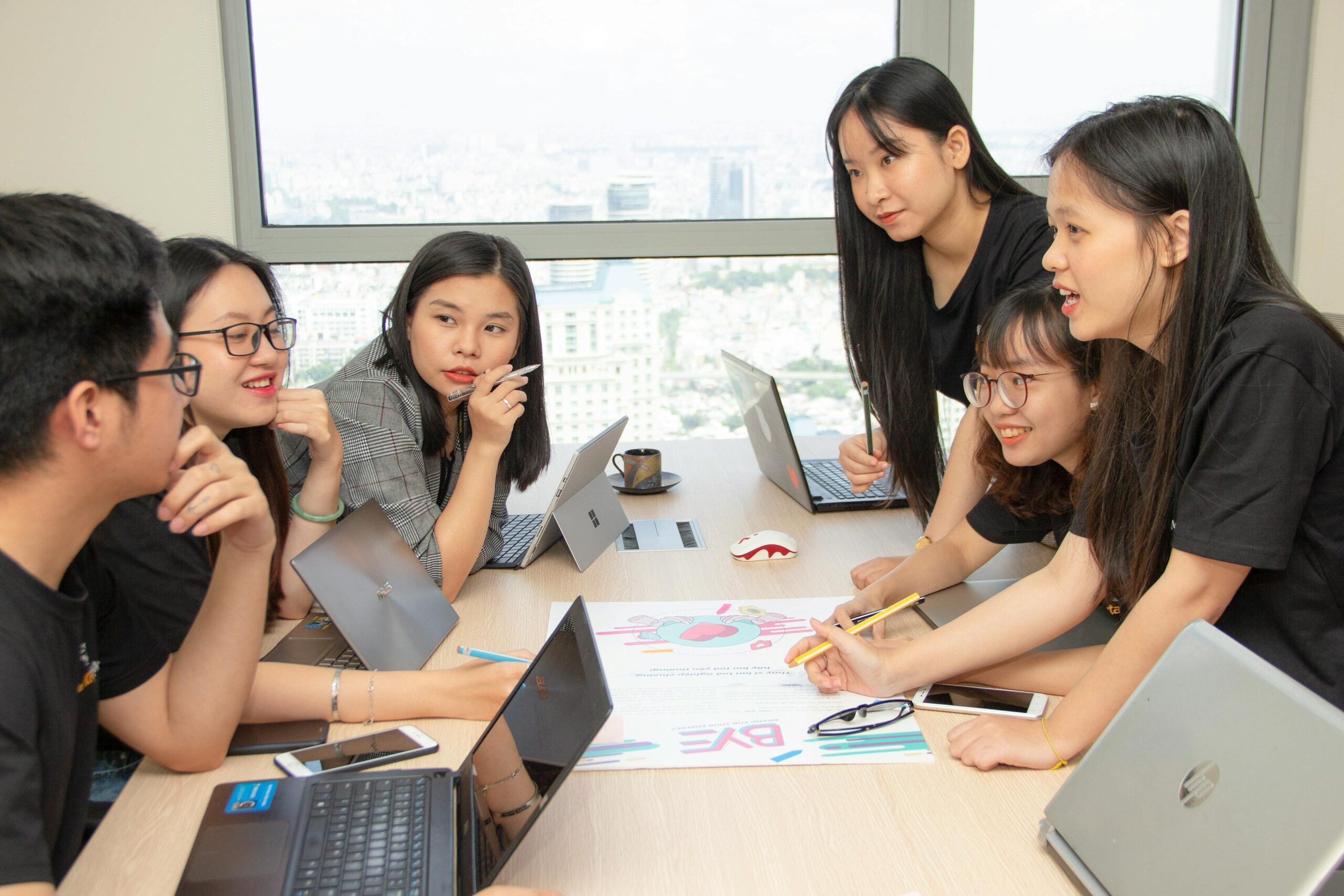 Professional team meeting in modern design studio with color swatches, candle vessel samples, prototypes, scent strips, and mood board visible on the table